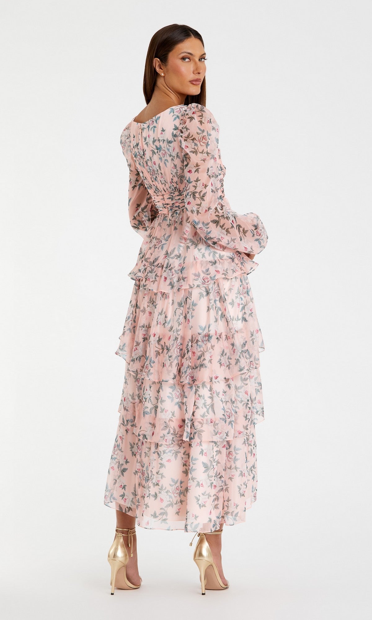 A woman models the Mac Duggal 55880 Print Midi Wedding Guest Dress with long sleeves and floral print, paired with gold heels, facing away with her head turned—an ideal chic choice for a wedding guest.
